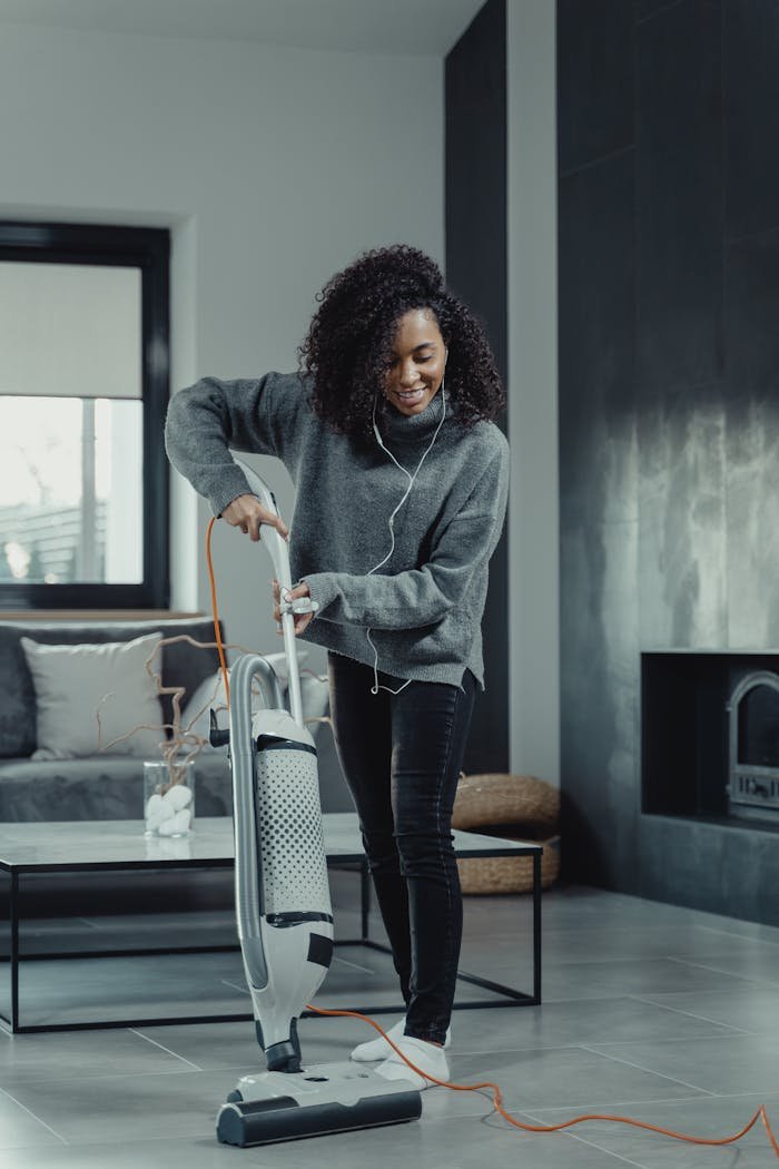 Smiling woman enjoying music while vacuuming a stylish living room.